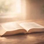 Bíblia aberta sobre superfície de madeira, iluminada por luz suave, simbolizando leitura e reflexão bíblica.