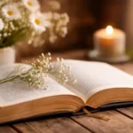 Bíblia aberta sobre mesa de madeira com flores brancas e vela acesa ao fundo, representando versículos para cura e fortalecimento da fé.